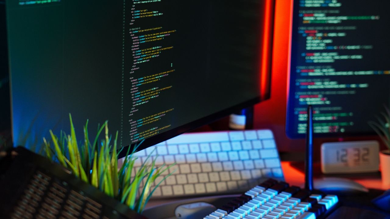 A vibrant workspace showing computer monitors with code, keyboard, and tech accessories.